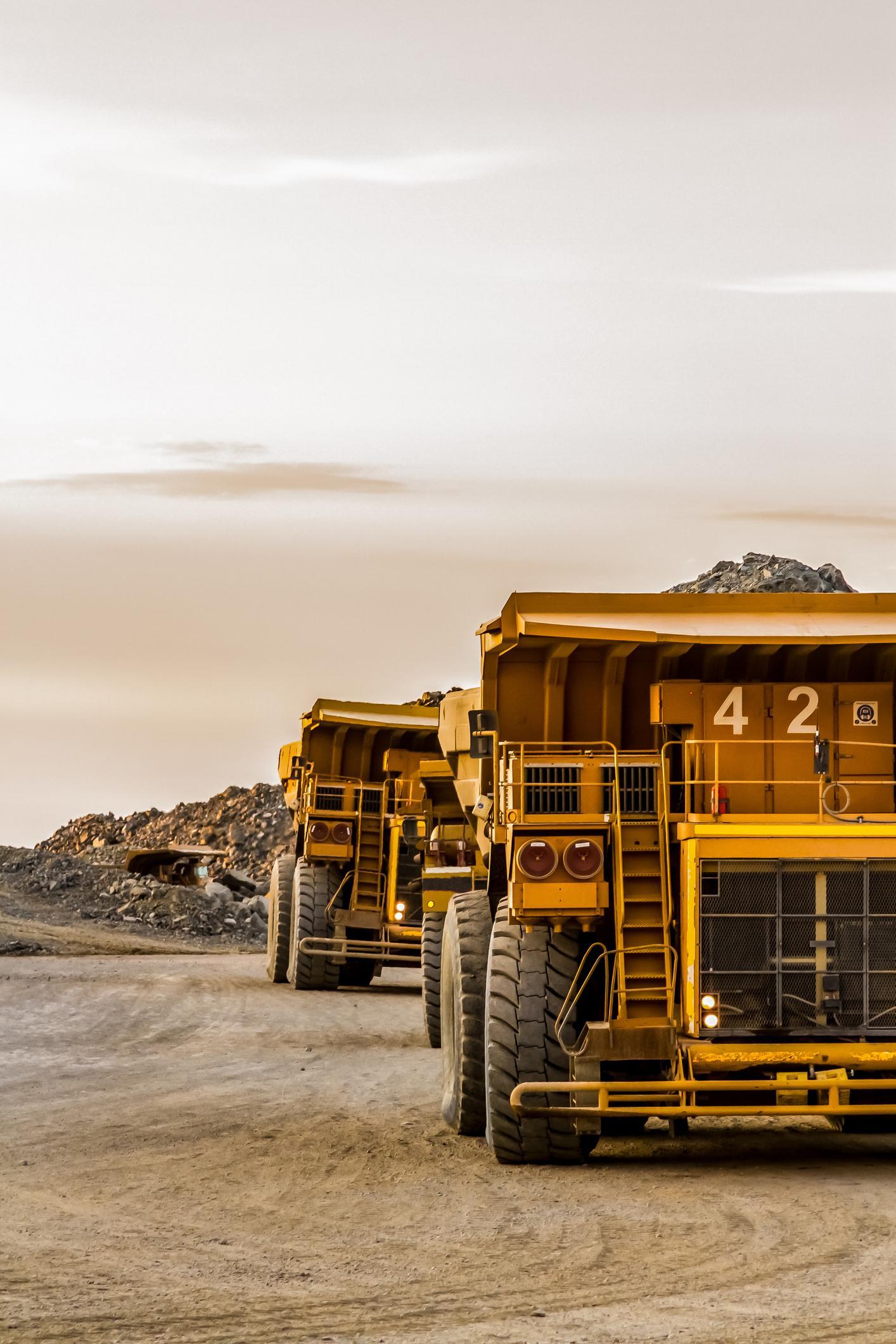 Dump trucks at quarry site transporting materials, handled by heavy-duty mining packaging solutions.