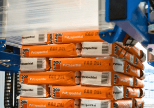 Stretch hood packaging equipment wrapping stacked products for flexible pallet protection.